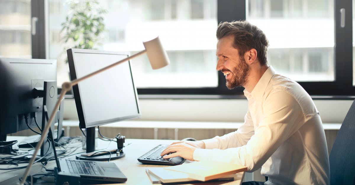 Lan on PC with a Windows 10 computer for Minecraft - Man in White Dress Shirt Sitting on Black Rolling Chair While Facing Black Computer Set and Smiling