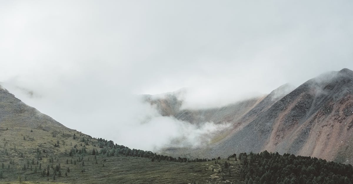 Land with wingsuit - Mountains and Terrains under Cloudy Sky Land with wingsuit - Mountains and Terrains under Cloudy Sky