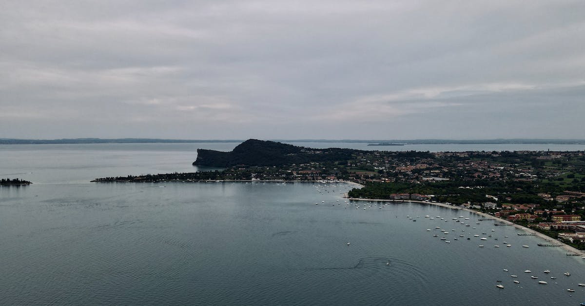 Last night, all the villagers disappeared from the village - Drone view of rippled sea with nautical transport near houses on mountain under sky at dusk