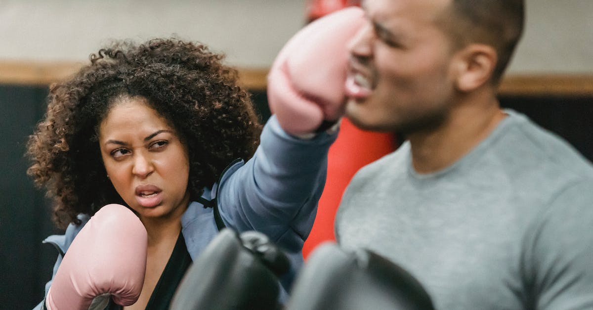 Last-Hit Challenge: How do I increase the duration? - Aggressive African American female fighter wearing gloves punching black coach in activewear while practicing exercise during boxing workout in gym