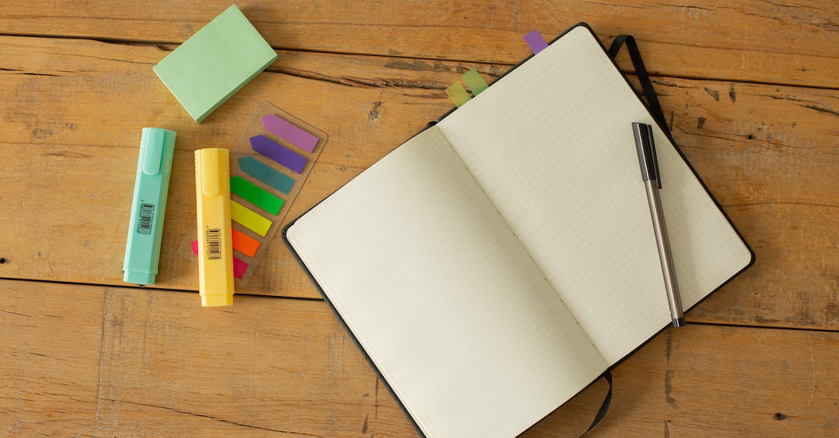 Learning new racial motifs - Top view of opened sketchbook with blank pages and pen with coloured markers and bookmarks arranged on wooden desk Learning new racial motifs - Top view of opened sketchbook with blank pages and pen with coloured markers and bookmarks arranged on wooden desk