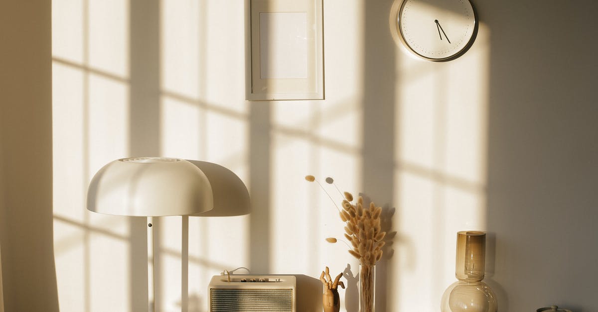 Light in my house without a source - Light room with retro radio and decorative vases with dry plants on desk near wall with clock and window shadow in sunlight Light in my house without a source - Light room with retro radio and decorative vases with dry plants on desk near wall with clock and window shadow in sunlight