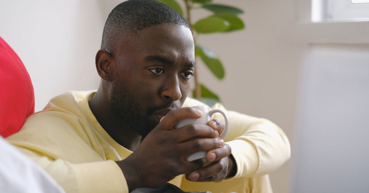 Loa: using deep space gates - Attentive black man drinking coffee against laptop on bed