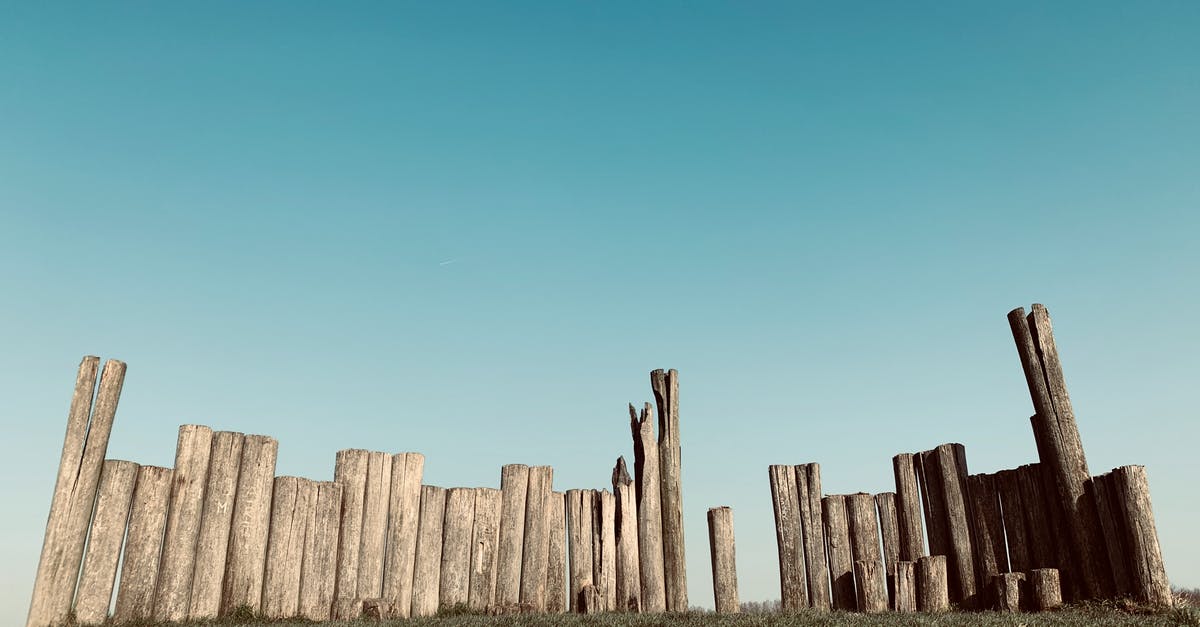 Load user-made structure blocks into different worlds iOS - Natural wooden fence of rounded tree trunks with shabby surface and cracks on grass meadow under cloudless sky in daylight in countryside