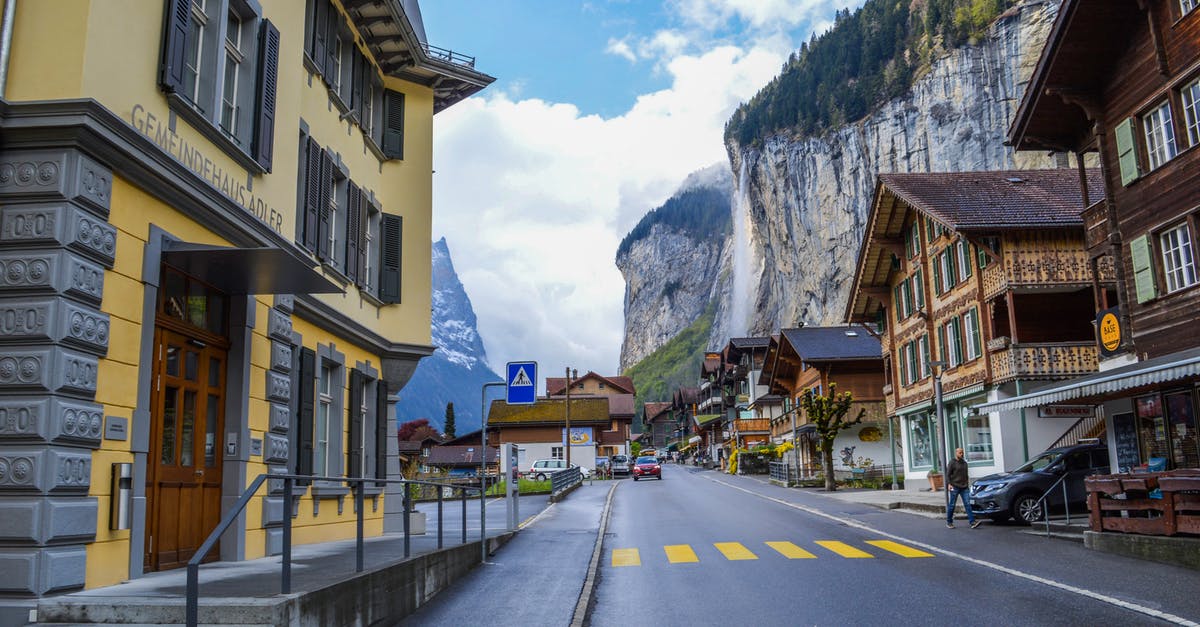 Locked myself out at the waterfall location - Street with asphalt road and low rise houses located near rocky mountains covered with green trees in cloudy day