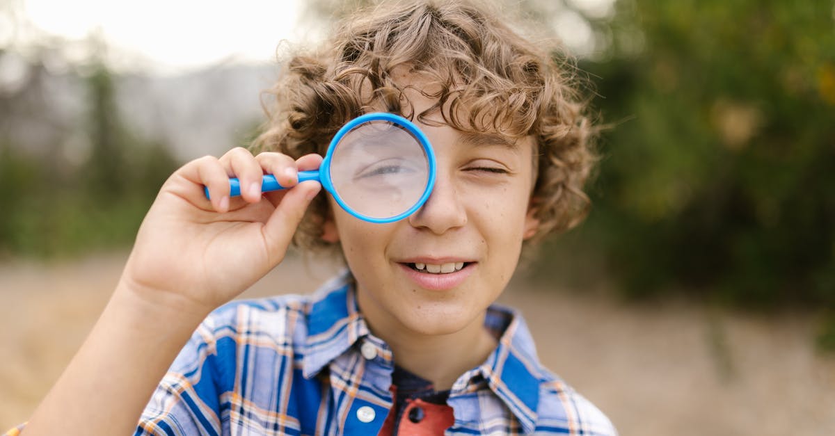 Looks through game reports in Battlefield 4 - Boy with Curly Hair Looking Through a Magnifying Glass on His One Eye Looks through game reports in Battlefield 4 - Boy with Curly Hair Looking Through a Magnifying Glass on His One Eye