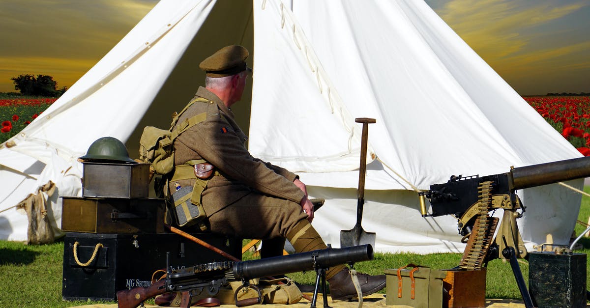 Machine Guns or Cannons? - Man Sitting on Chair Near White Tent