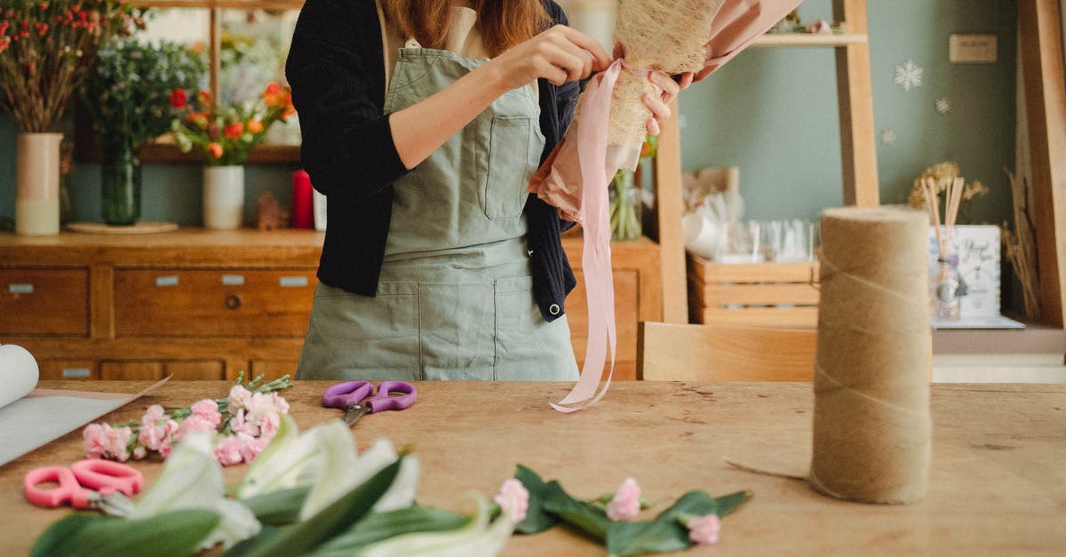 Make mushroom/fire flower blocks alternate - Crop unrecognizable female florist wearing apron standing near table in contemporary light floristry shop and arranging bouquets Make mushroom/fire flower blocks alternate - Crop unrecognizable female florist wearing apron standing near table in contemporary light floristry shop and arranging bouquets