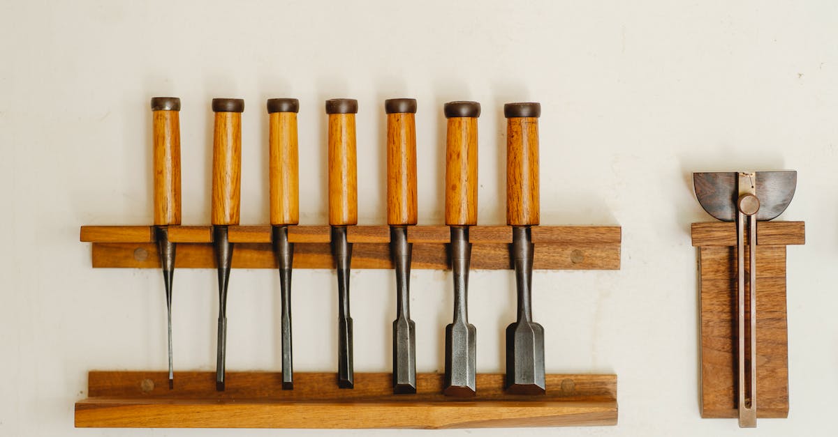 Manually set items transferred with a train - Collection of metal chisels with wooden handles and wood cutters for woodwork arranged on shelf on white wall in workshop