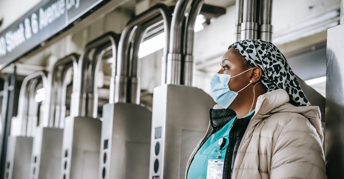 MCSM season 2 episodes and season pass 'unavailable' - Side view emotionless African American female doctor wearing warm clothes and protective face mask passing through turnstile gates in New York underground