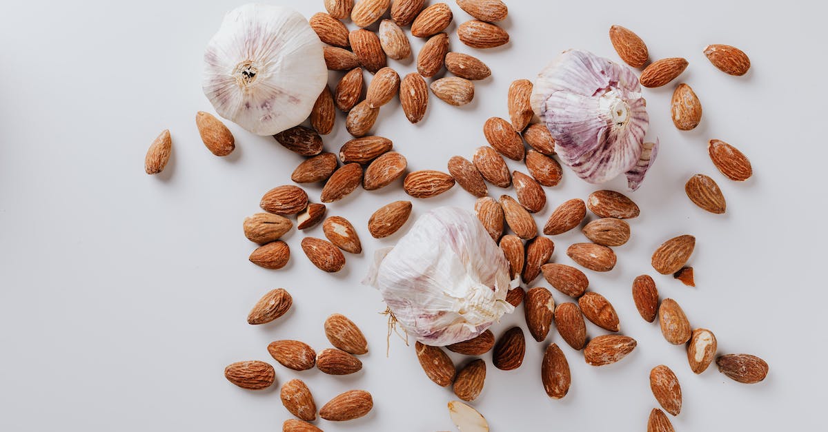 Menu selector is impossible to distinguish by colour - Raw almonds and heads of garlic on white background Menu selector is impossible to distinguish by colour - Raw almonds and heads of garlic on white background