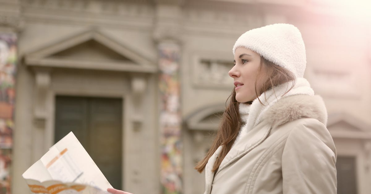 Mercer's Plans seem to appear outside of a map - Side view of female traveler in warm clothes and head wear studying map while standing near antique building Mercer's Plans seem to appear outside of a map - Side view of female traveler in warm clothes and head wear studying map while standing near antique building