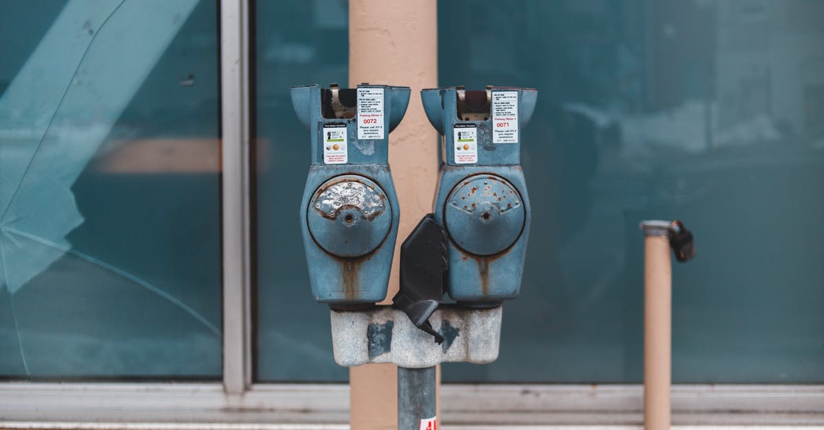 MHW How to enable damage meter in training area? - Old metal coin operated timer with rusty uneven surface on post near house window with crack reflecting town in daylight