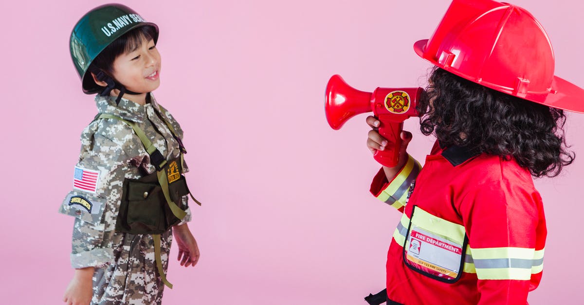 Military uprising and other problems in Tropico 5 - Side view of multiethnic kids wearing navy uniform and firefighter costume with loudspeaker standing together on pink background in hardhats and looking at each other