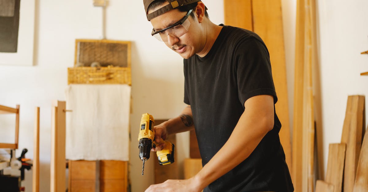 Minecraft 1.6.2 Cannot Craft Drill or Chainsaw - Young attentive ethnic male carpenter in protective glasses with drilling machine and timber in workroom