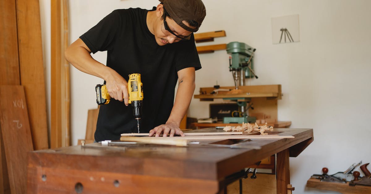 Minecraft 1.6.2 Cannot Craft Drill or Chainsaw - Focused man in cap standing near workbench and drilling hole in plank while repairing wooden detail