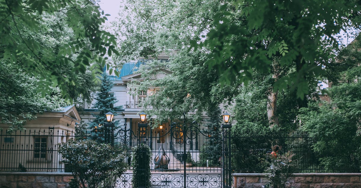 Minecraft forge 1.7.2 [closed] - Exterior of stylish classic styled mansion with forged fence and elegant street lamps surrounded by lush green trees in daytime