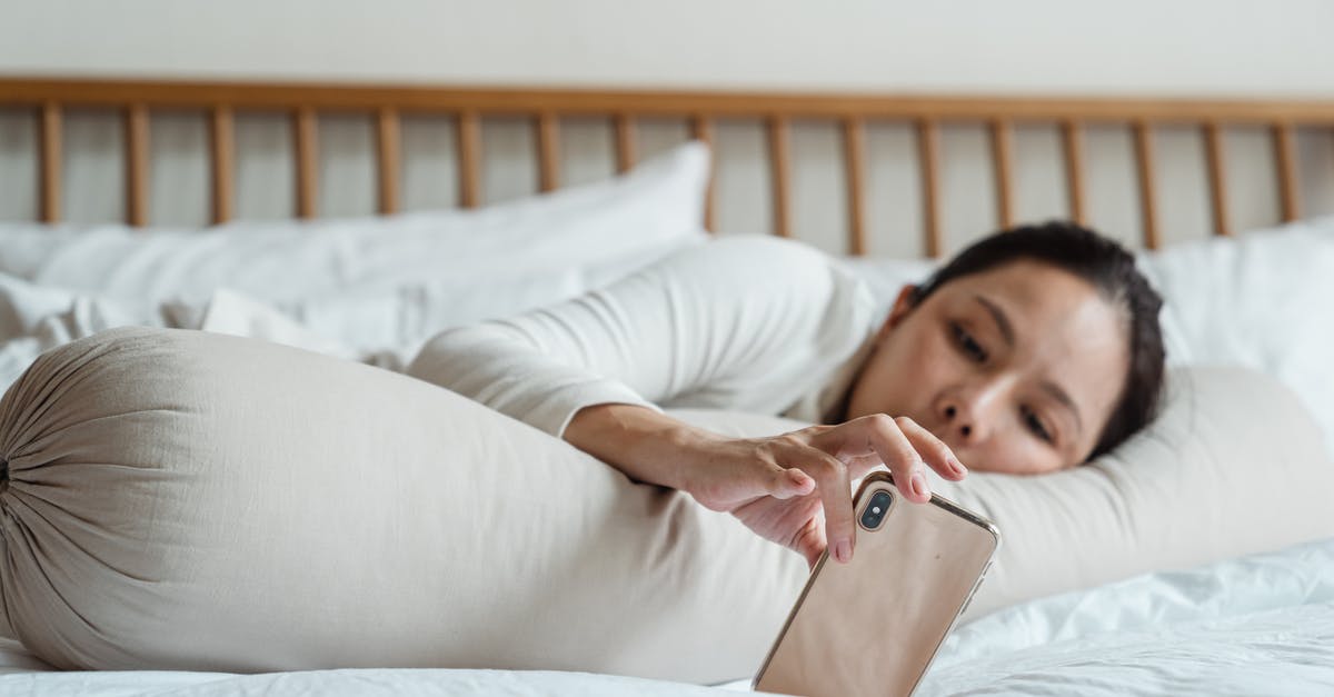 Minecraft LAN connecting to server for long time [duplicate] - Content young ethnic female watching video on cellphone while lying on comfortable bed with long cylinder pillow in morning and enjoying free time