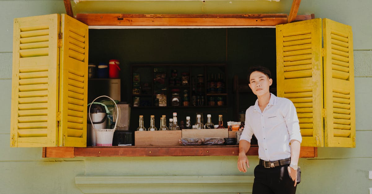 Minecraft Pocket Edition Local Multiplayer - Young dreamy ethnic guy in stylish clothes standing with hand in pocket near window of old building with refreshing drinks for sale while looking at camera Minecraft Pocket Edition Local Multiplayer - Young dreamy ethnic guy in stylish clothes standing with hand in pocket near window of old building with refreshing drinks for sale while looking at camera