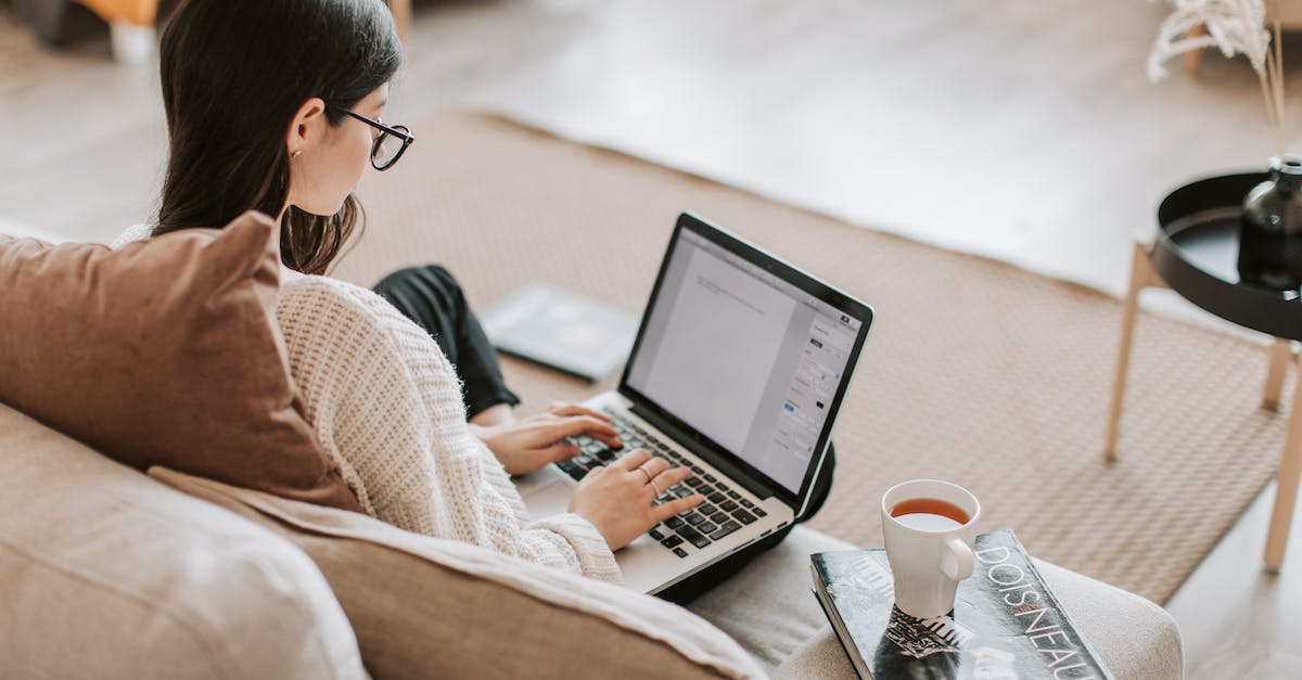 Minecraft wont maximize after entering and leaving full screen [duplicate] - From above back view of full length female freelancer with crossed legs sitting on cozy sofa with cup of tea on book while typing text on laptop