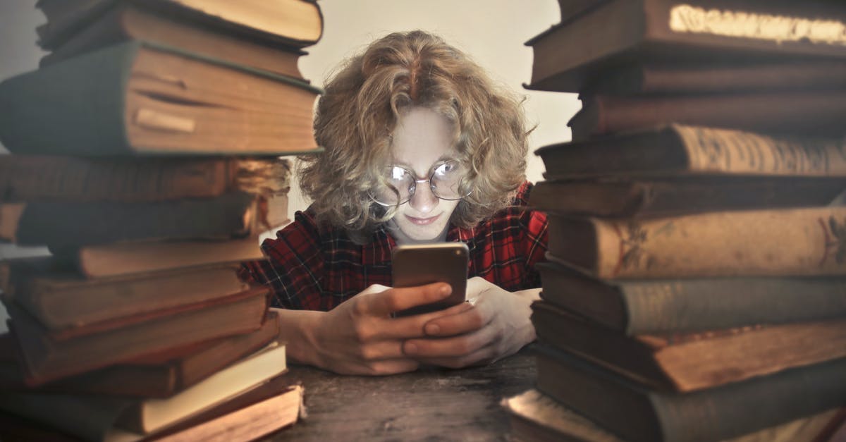 Minecraft world generation differs using exact same seed - Focused male student in casual wear and glasses browsing smartphone while sitting at wooden table with stacked old books