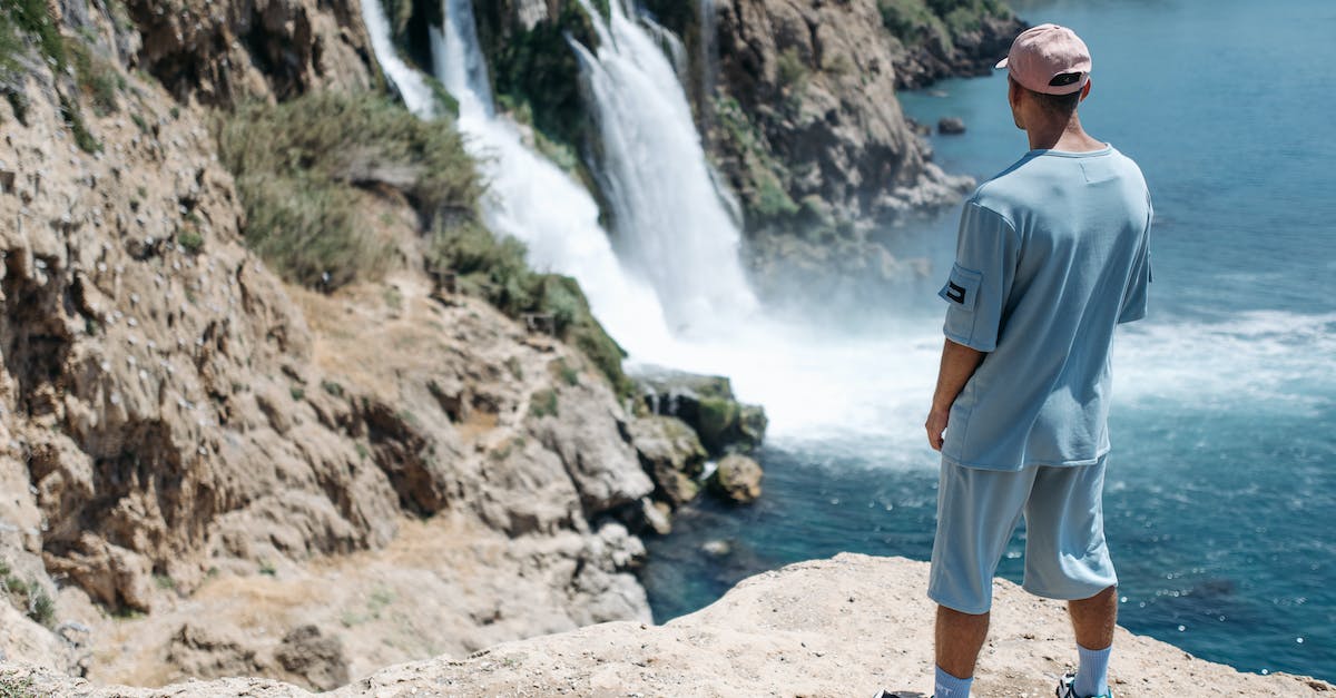 Mitigation Cap on Portals - Man in a Blue Shirt Standing Near a Waterfall