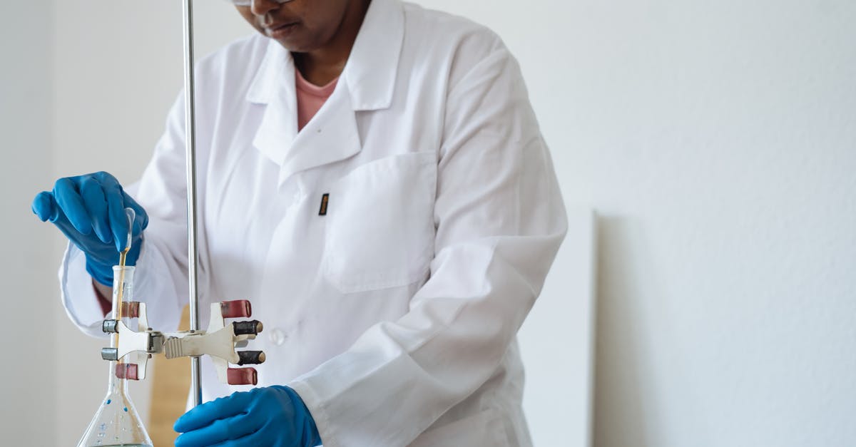 Mob Health Check [duplicate] - Serious laboratory technician dressed in uniform and safety glasses carrying out titration during work in laboratory inserting pipette into flask with reagent