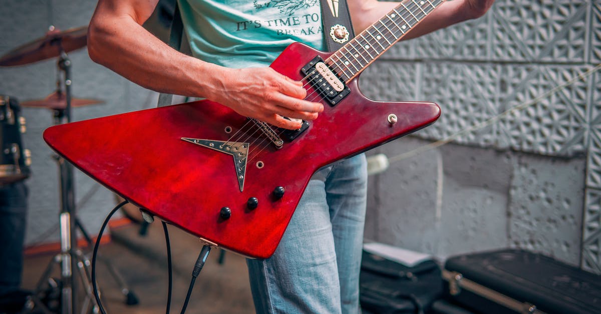 More Songs for Rock Band 4 - Crop male musician in tee shirt and jeans standing and playing red electric guitar with drums behind More Songs for Rock Band 4 - Crop male musician in tee shirt and jeans standing and playing red electric guitar with drums behind