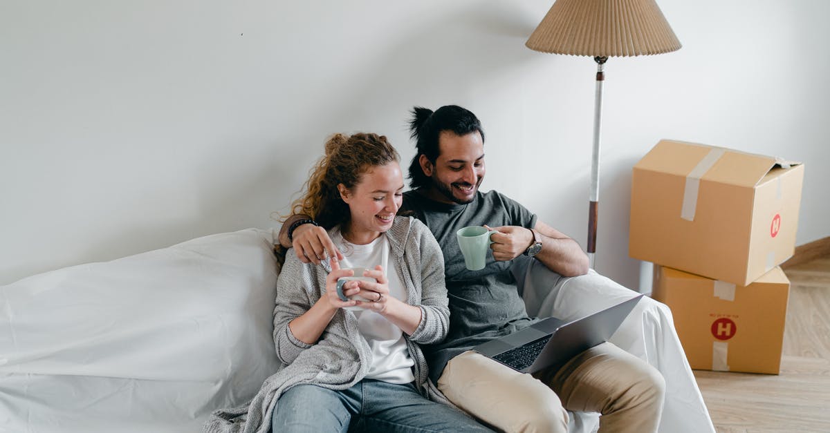 Move online resources to offline resources - Multiethnic couple embracing on couch while watching laptop at home