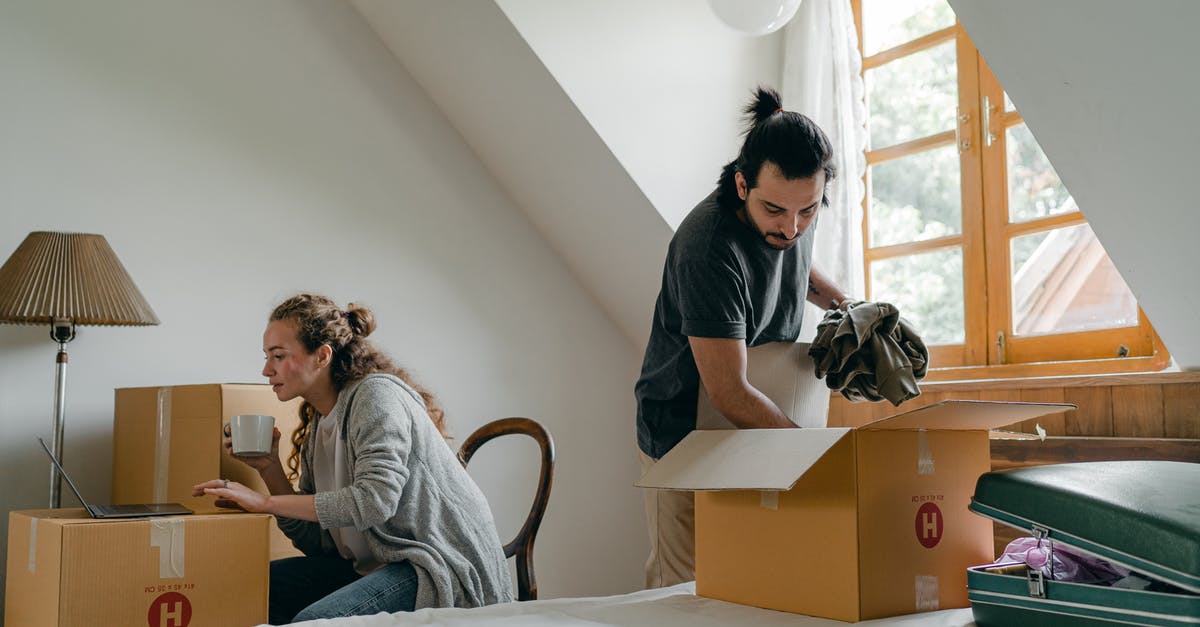 Move online resources to offline resources - Ethnic boyfriend unpacking box while woman using laptop at home Move online resources to offline resources - Ethnic boyfriend unpacking box while woman using laptop at home