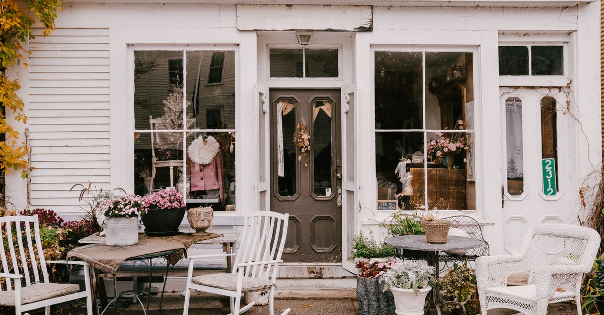 Moving furniture from one settlement to another [duplicate] - Exterior of empty terrace of old residential house with potted flowers and chairs with round tables