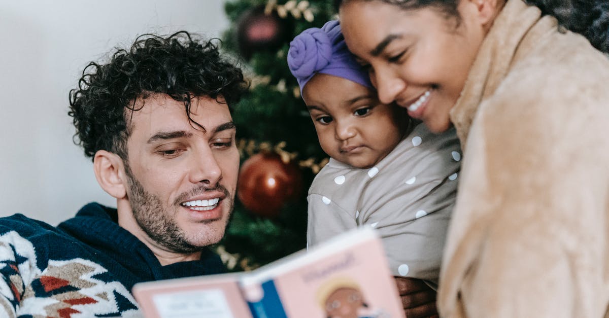Multiple book click events - Happy African American mother and ethnic father reading book to little black daughter near decorated tree during Christmas celebration at home