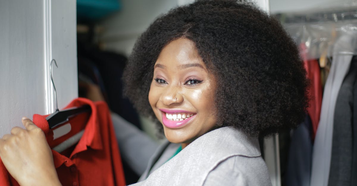 My follower attacks me when I pick up stolen items in my house - Cheerful young ethnic lady choosing clothes near wardrobe in room