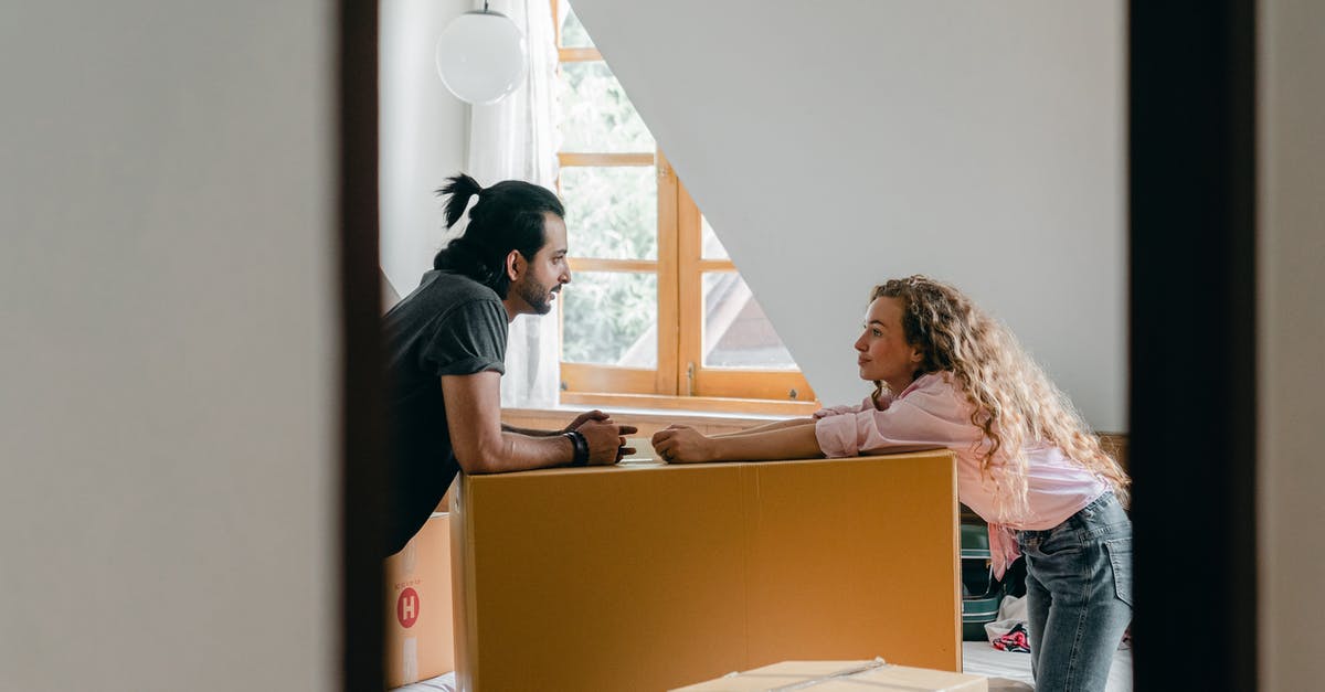 My two kids won't move to my new house [duplicate] - Side view from entrance of cheerful young ethnic bearded man with ponytail and woman with curly hair leaning on large cardboard package while arranging stuff in cozy attic bedroom