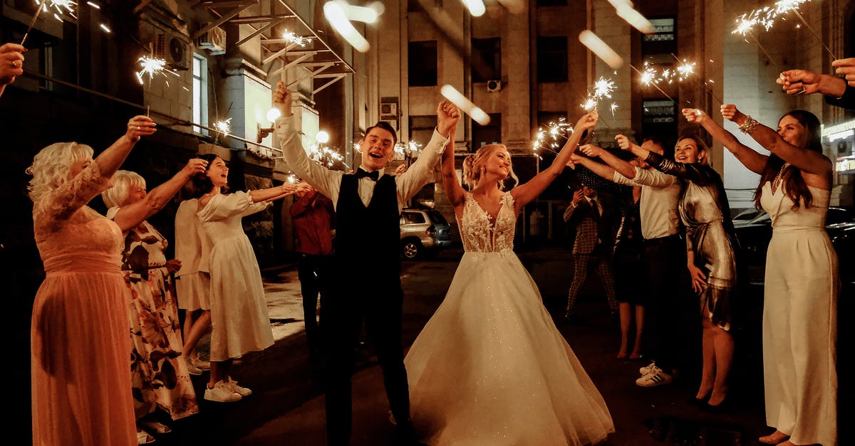 My wife disappeared, but we're still married. How can I fix this? - Cheerful young bride and groom with guests dancing on street with sparklers in hands during wedding party