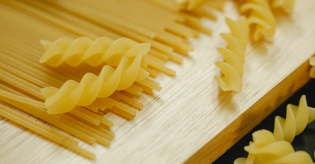 Name of the recipe for this type of wall? - From above closeup of fusilli and spaghetti placed on wooden board for cooking dish