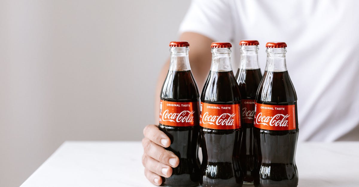 Nearby tracker doesn't refresh - Crop anonymous young male in white t shirt demonstrating glass bottles of coke while sitting at table