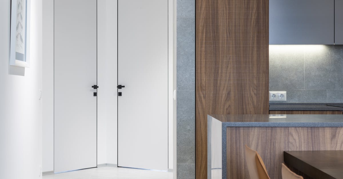New liset segment - Hallway with white doors and walls near wooden kitchen counter with cupboards near table and chairs in modern apartment at home New liset segment - Hallway with white doors and walls near wooden kitchen counter with cupboards near table and chairs in modern apartment at home