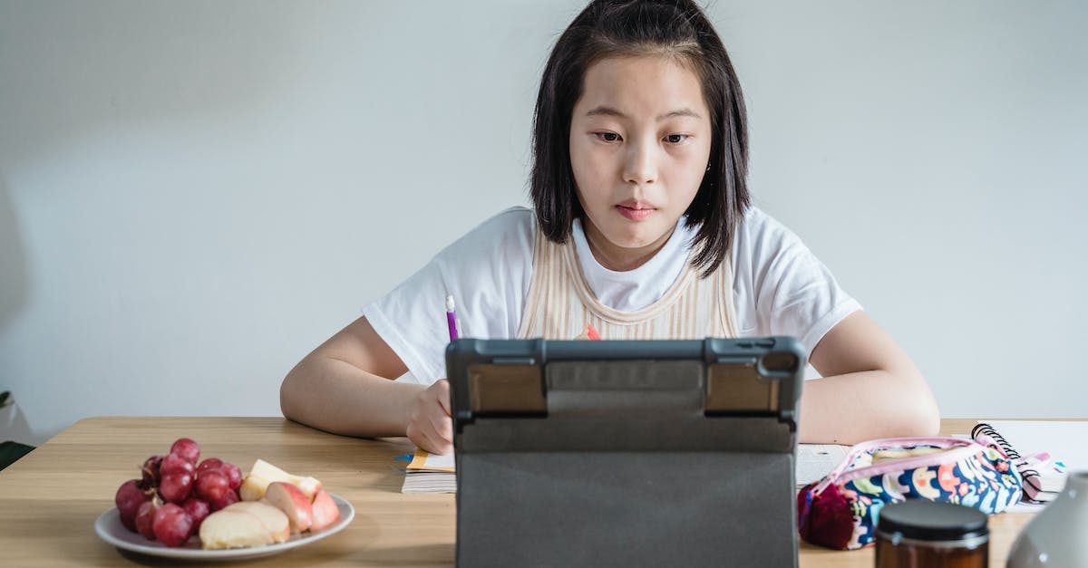 No moving on iPad - A Young Girl Studying and Looking on an iPad on a Table