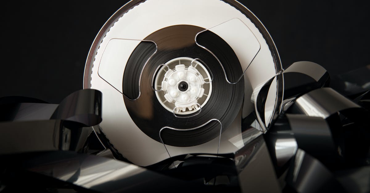 Obsolete Material - Vintage plastic bobbin with unrolled film for cinematography industry placed on black background Obsolete Material - Vintage plastic bobbin with unrolled film for cinematography industry placed on black background