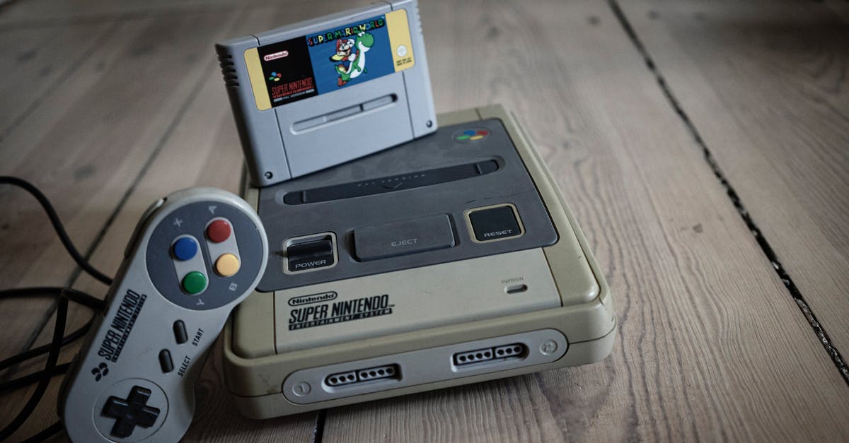 Old controller not connecting - From above of aged video game console with cassette and controller with colorful buttons on wooden surface