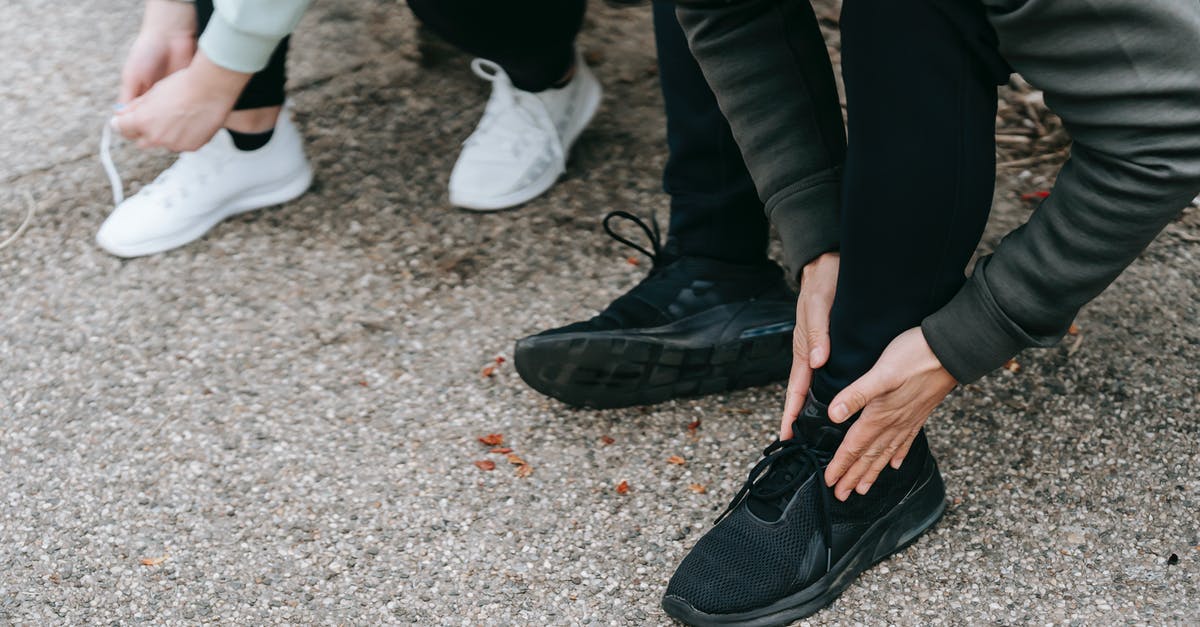 On what basis are tie-breakers decided in asphalt 8? - Crop unrecognizable people in warm sportswear tying shoelaces of sneakers on street in daytime