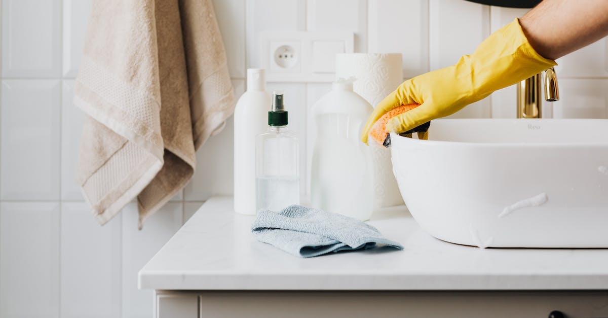 Only one housekeeper cleans an entire floor? - Person in glove wiping surface of sink in modern bathroom Only one housekeeper cleans an entire floor? - Person in glove wiping surface of sink in modern bathroom