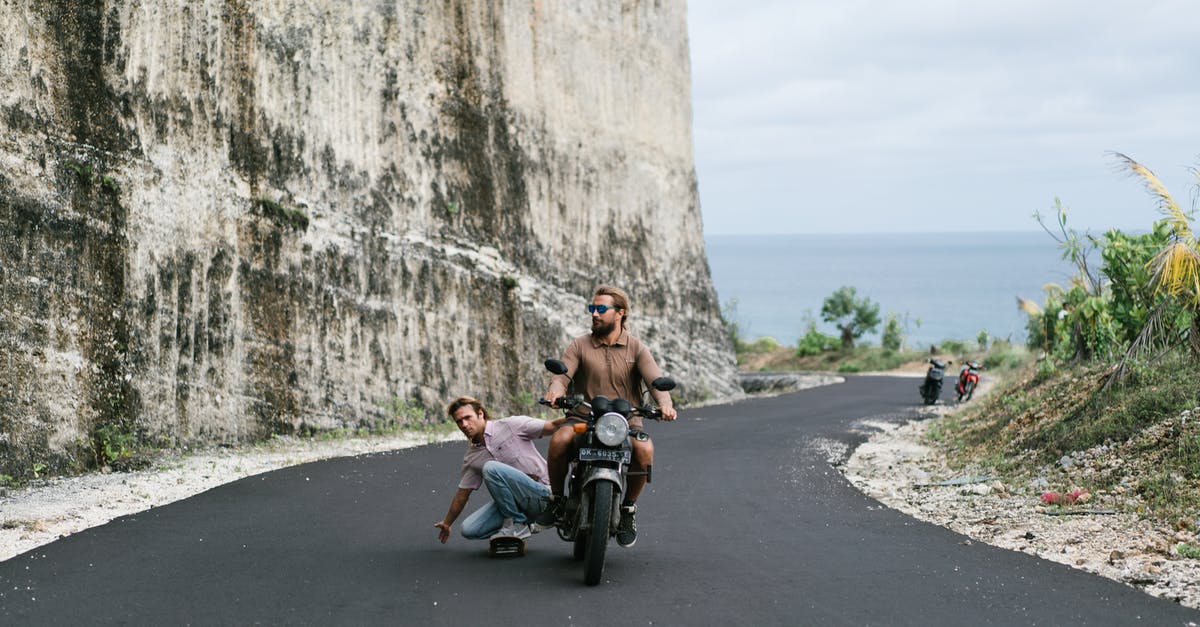 Optimal First Clear Route for Gragas? - Full body man in casual wear riding skateboard while being pulled by biker on modern motorbike along asphalt road on picturesque seaside