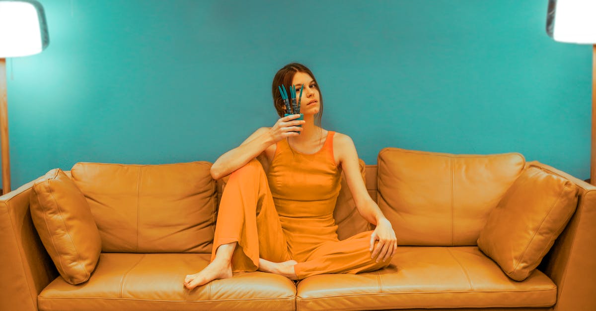 Options for boosting signal over DSL/live match for Xbox 360 - Full body of focused barefoot female wearing casual clothes sitting with bent leg and pot with flower near face on sofa near green wall in room