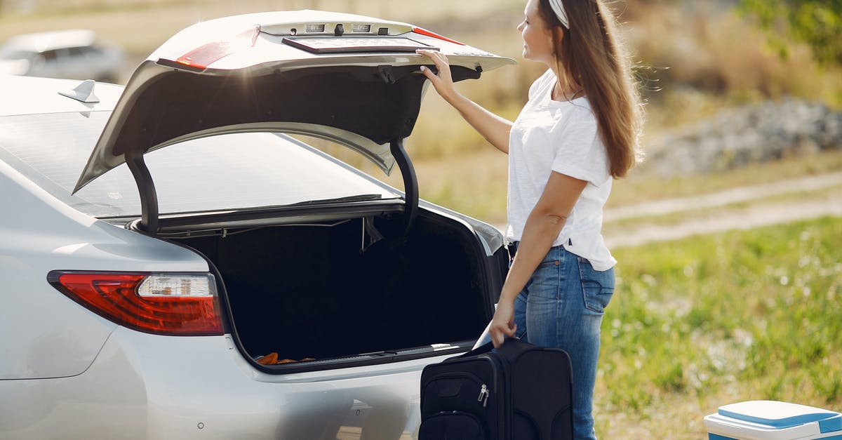 Origin doesn't load the game! - Side view of cheerful female traveler in headband and casual clothes putting luggage in open trunk of modern car while spending summer weekend in countryside