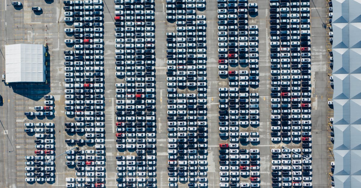 Parks in industrial areas? - Aerial view of various modern vehicles parked in row on street near modern building on sunny day Parks in industrial areas? - Aerial view of various modern vehicles parked in row on street near modern building on sunny day