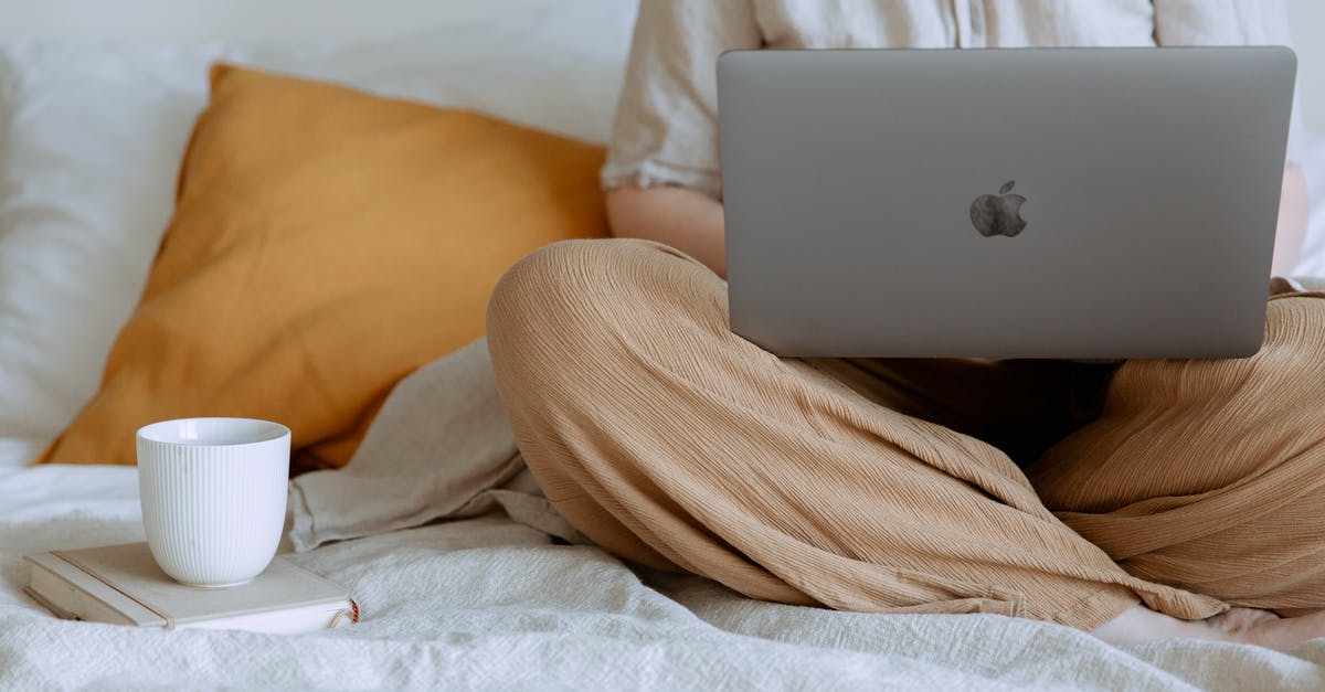 Place a complete bed using /setblock - Crop faceless female in casual outfit sitting on bed with legs crossed holding laptop on knees with cup of coffee standing on notebook while working from home