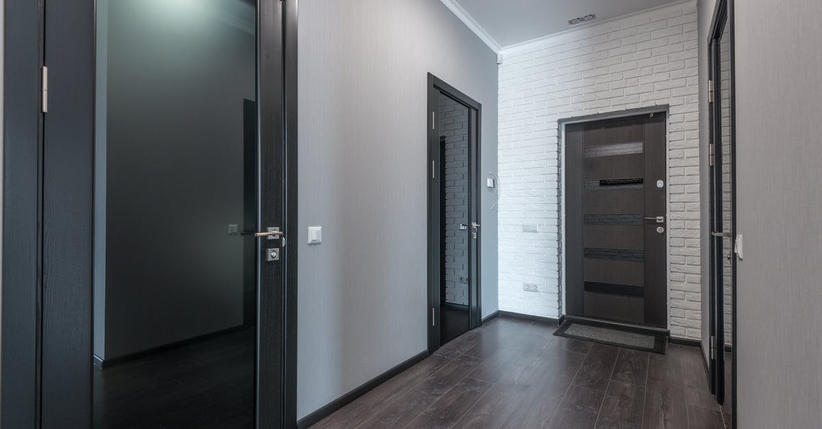 Placing Skulls/Heads Inside Glass Blocks - Interior of empty spacious corridor with laminate floor and black doors with glass parts and white ceiling and gray painted walls