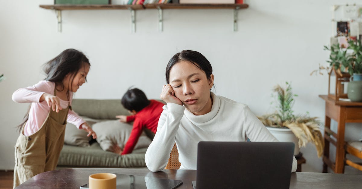 Play online without expansion packs - Tired ethnic working mother at home with playing kids Play online without expansion packs - Tired ethnic working mother at home with playing kids